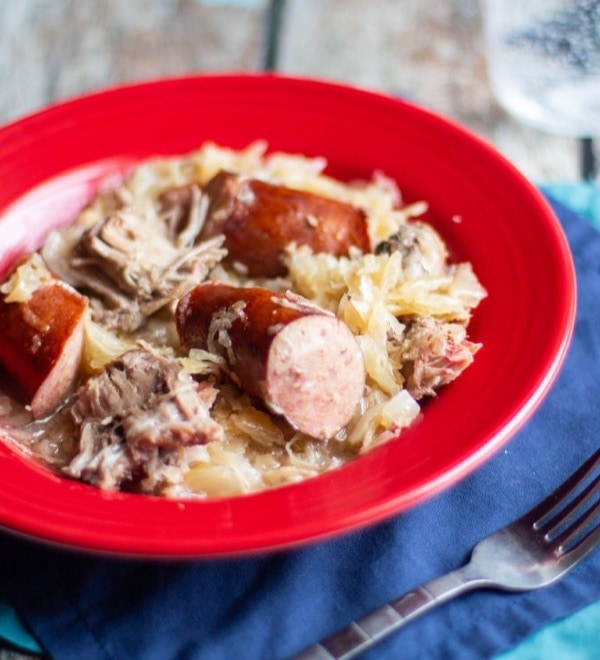 Bowl of Kielbasa, chunks of Pork Shoulder, and sauerkraut in a red bowl ready to eat