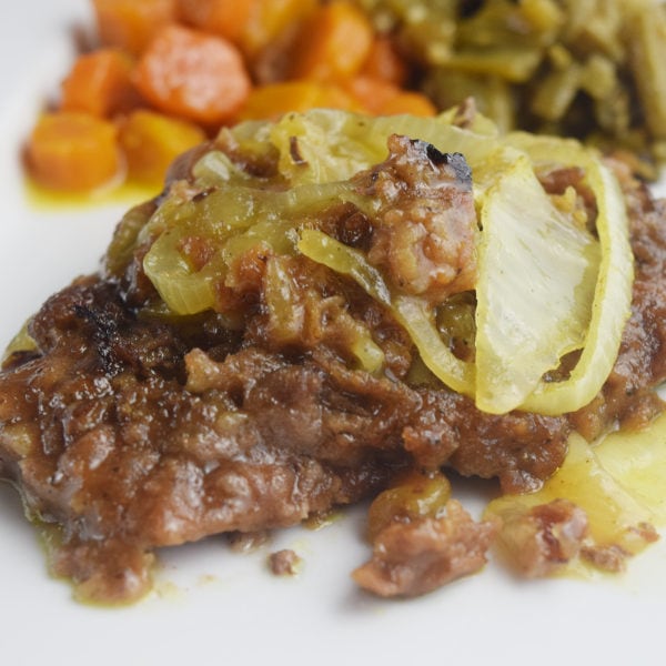 cube steak smothered in onions with a side of green beans and carrots