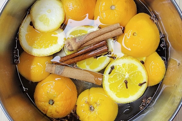 orange slices, 3 cinnamon sticks, whole cloves and whole allspice in a pot for simming a stovetop potpurri recipe