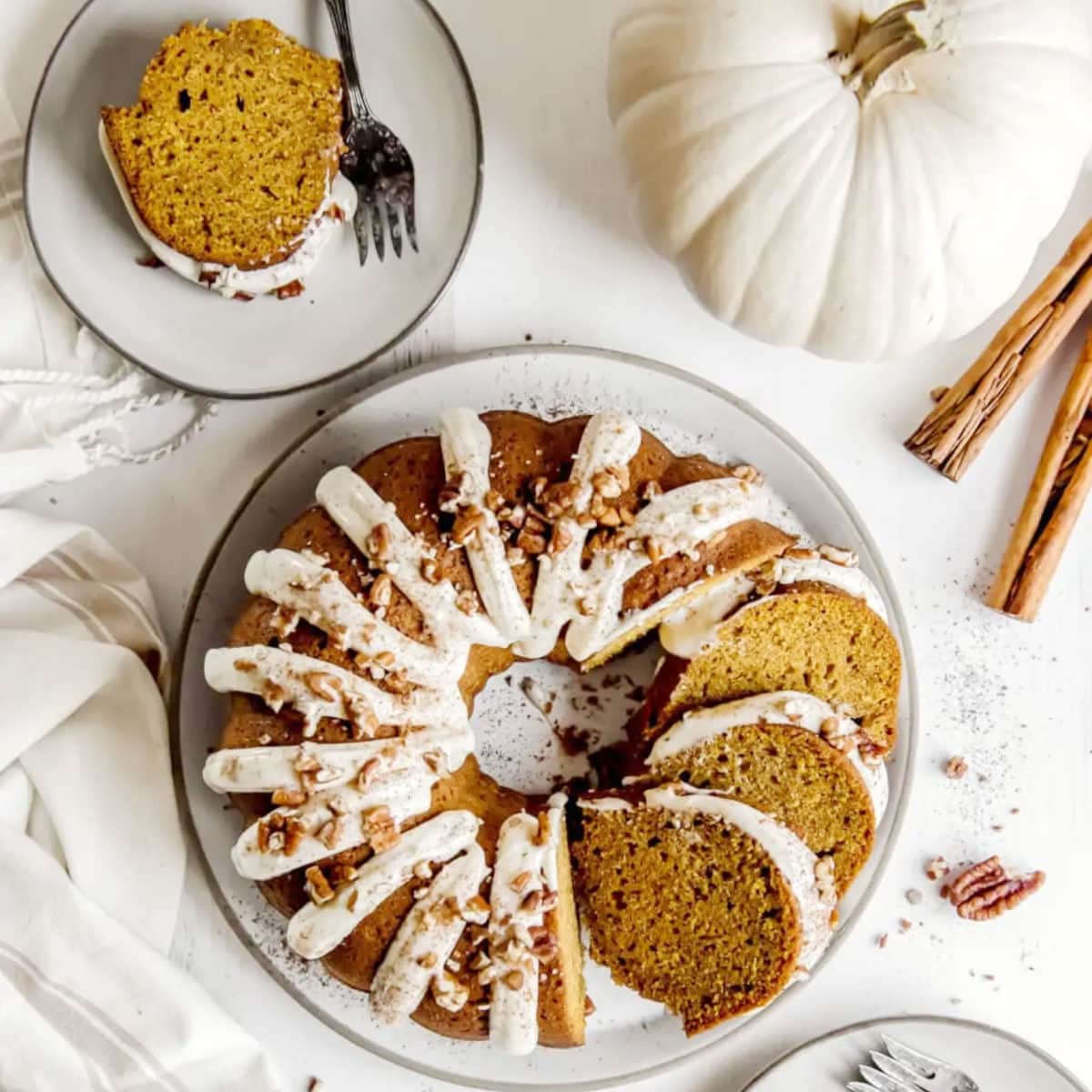 pumpkin cake recipe bundt sliced on a platter with a white pumpkin