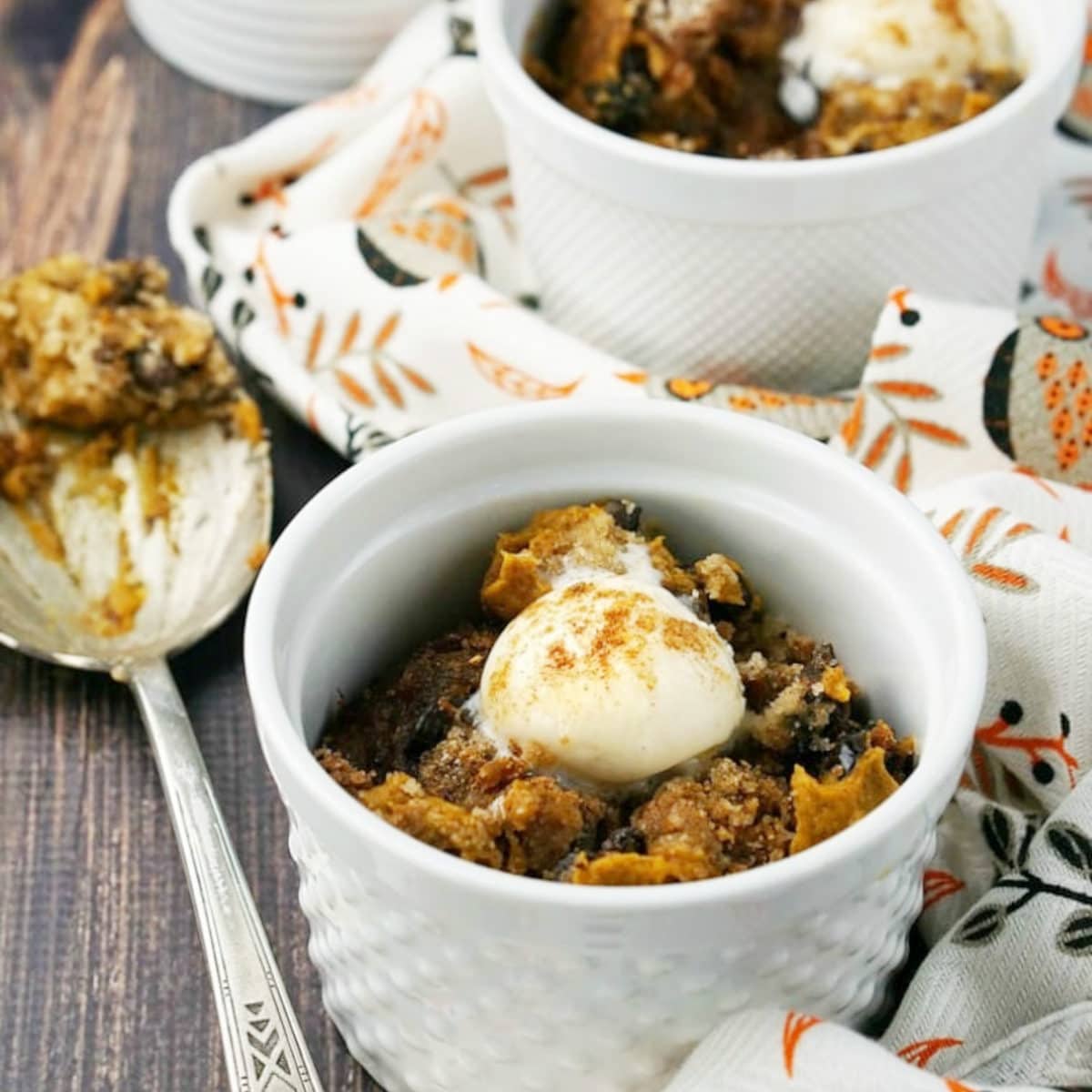 pumpkin dump cake from a crockpot in a bowl with a scoop of icing on top