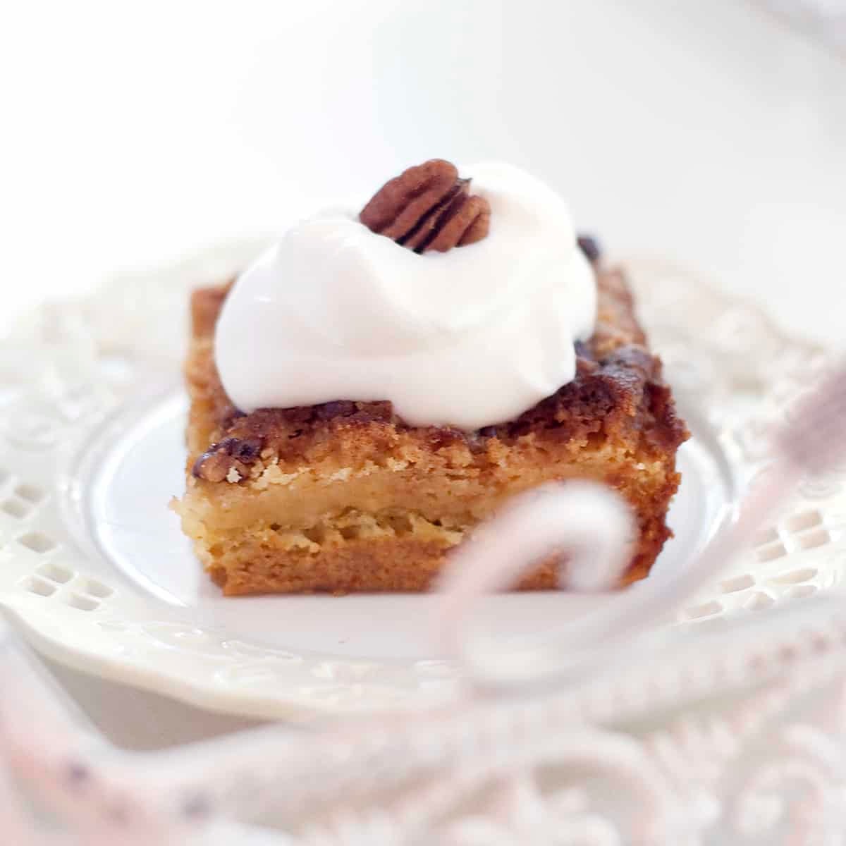 pumpkin cake on plate with scoop of cool whip and a pecan on top