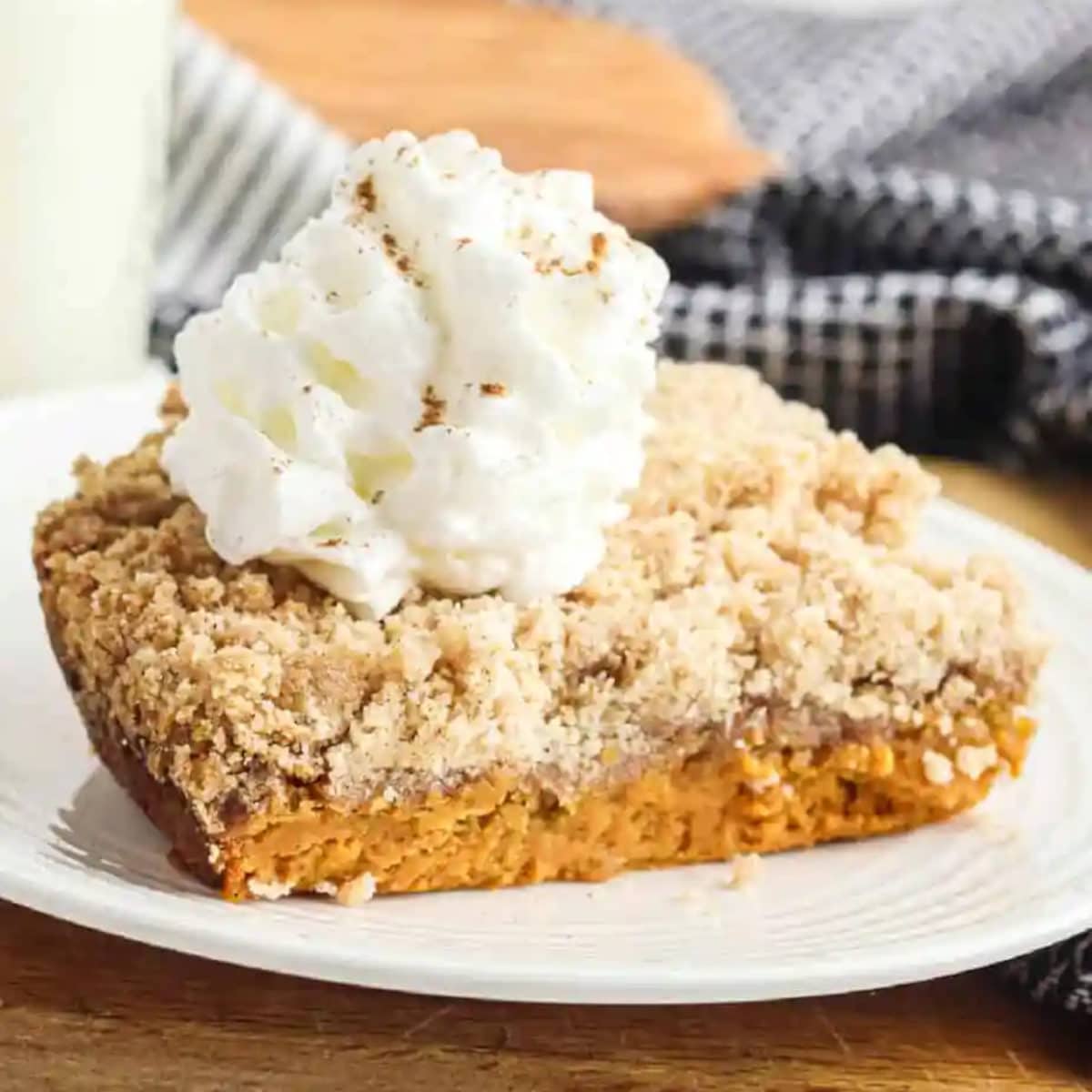 pumpkin dump cake sliced on a plate with scoop of whip cream