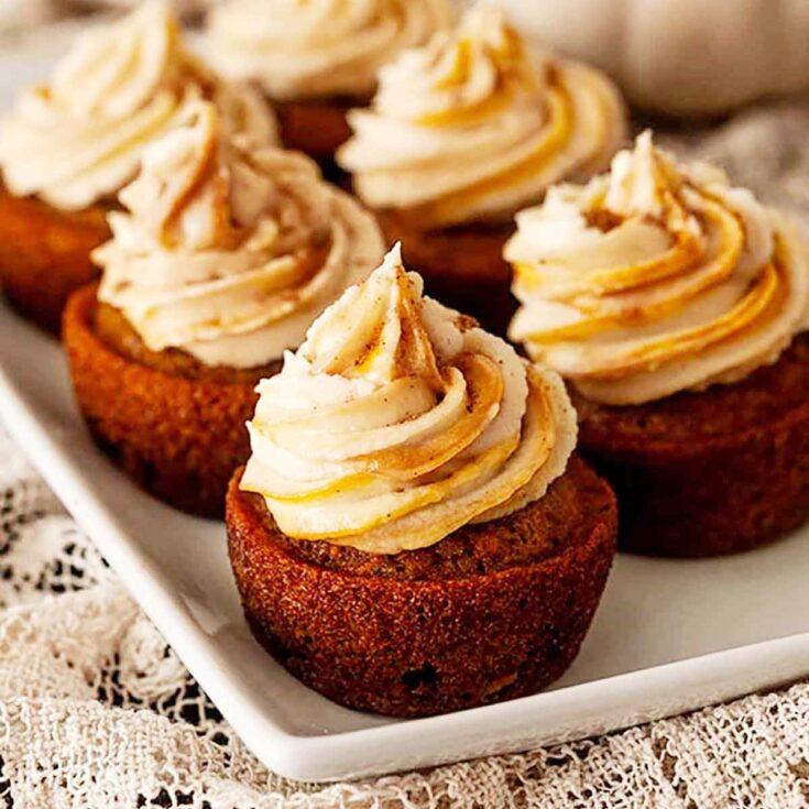 6 pumpkin cupcpake with cinnamon cream cheese frosting on a plate