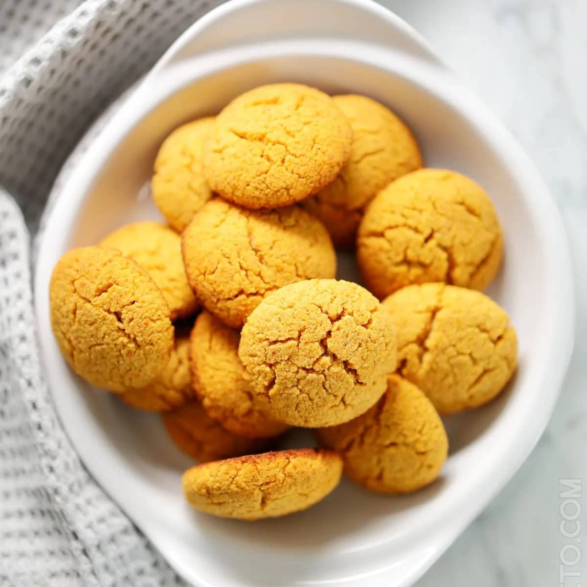 bowl full of golden orange pumpkin cookies on a counter