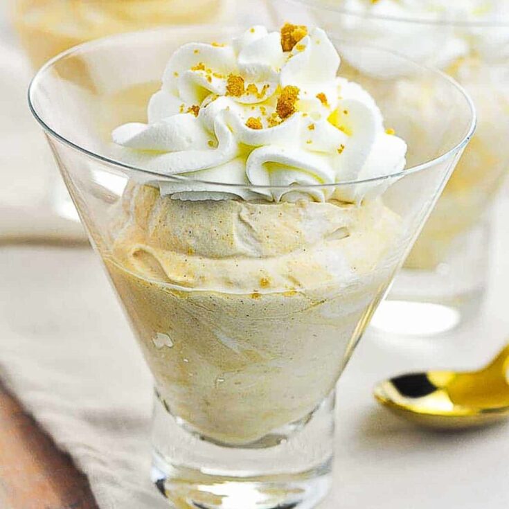 Pumpkin cheesecake mousse with whip cream and cinnamon topping in a clear glass