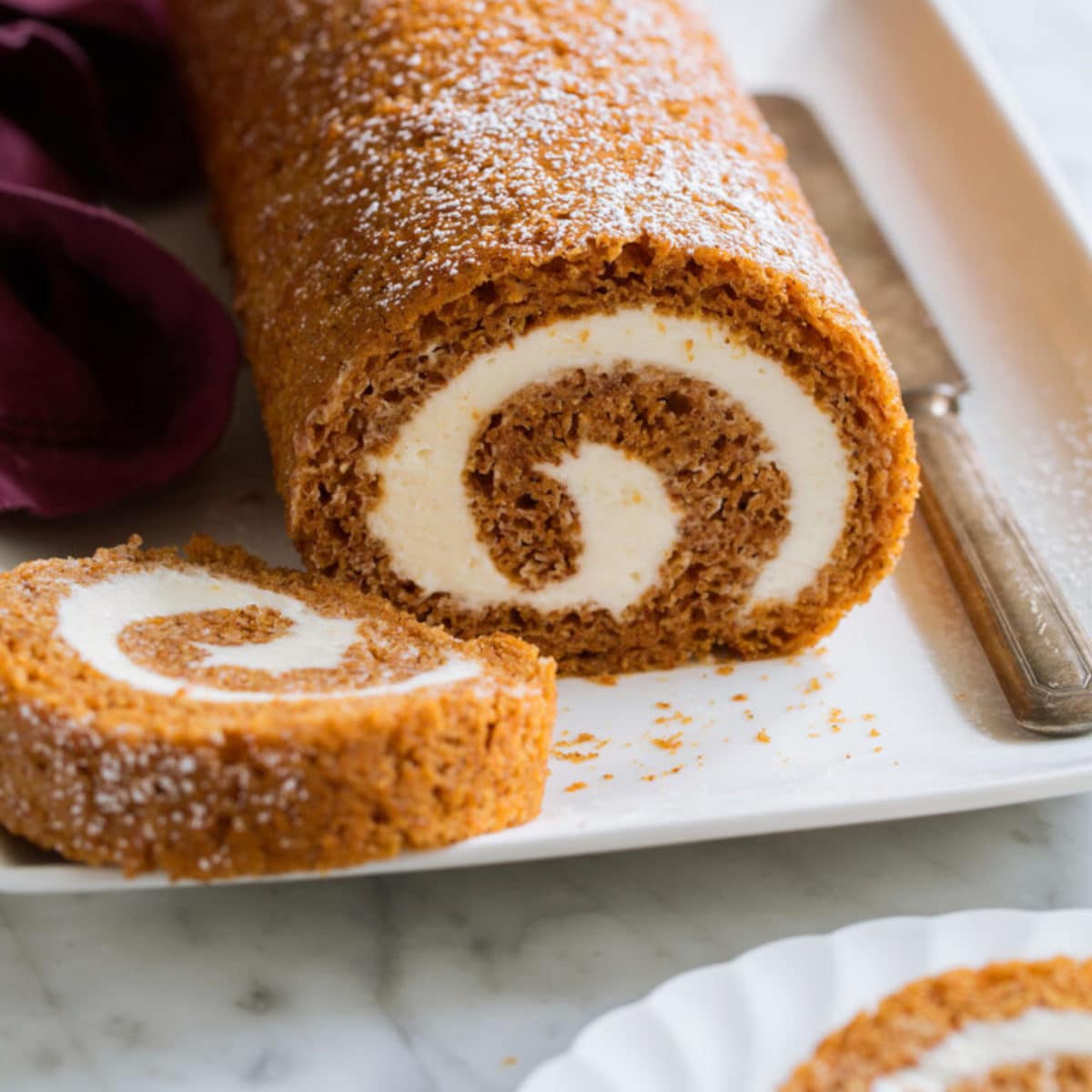 pumpkin roll on a white plate with butter knife to the right