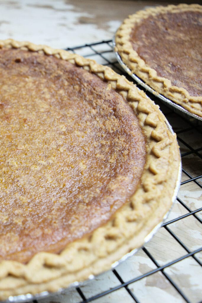 2 old-fashioned pumpkin pies on a cooling rack