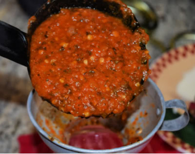 pizza sauce in a ladle filling jars