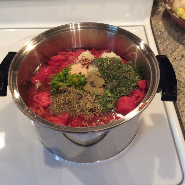 homemade pizza sauce with herbs, and frozen tomatoes in a pot