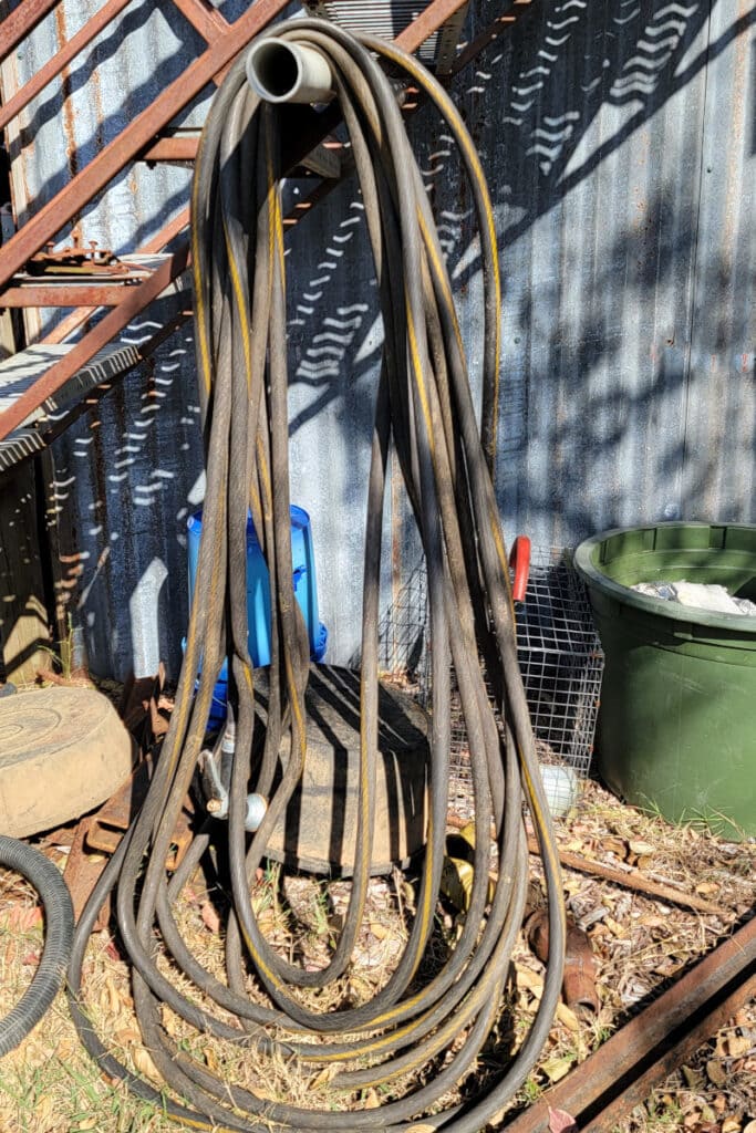 black rubber water hose hanging on a pipe